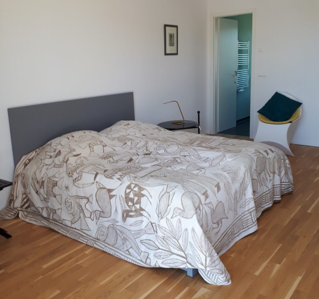 Bett, dahinter Tür zum Duschbad